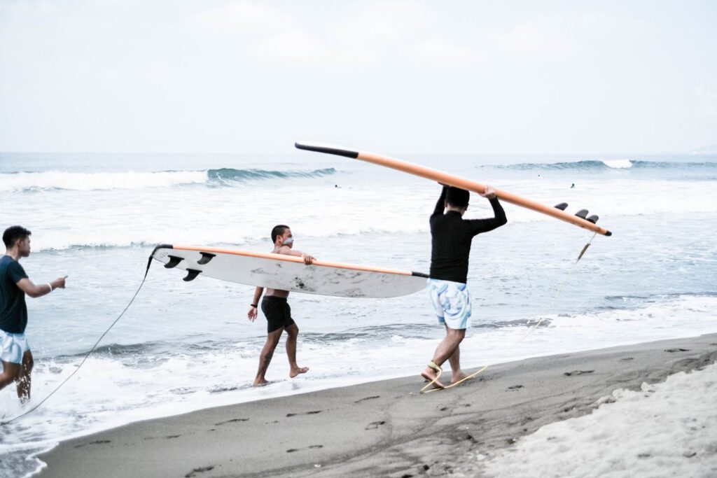 La union fillipines two men carrying their surfboards on the beach